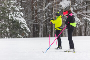 A couple of skiers are preparing for a cross-country in the forest
