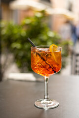 Aperol Spritz Cocktail. Alcoholic beverage based on table with ice cubes and oranges outdoors. Served cocktail with orange slice and straw placed on the table of sidewalk cafe in Italy