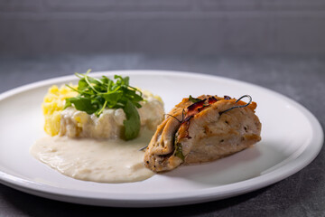 turkey roll filled with spinach and ham served with mashed potatoes and cream sauce