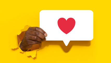 Black man holding bubble with heart through hole in paper