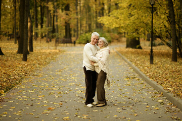 Fototapeta premium Elderly couple dance in the park in autumn.