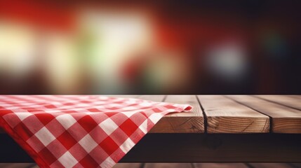 Red checkered folded picnic cloth on wooden table empty space background.Towel over the plank blurred kitchen background.