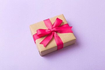 Wrapped christmas or other holiday handmade present in craft paper with colored ribbon. Present box, decoration of gift on table, top view with copy space