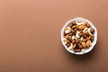 Assortment of nuts in wooden bowl on colored table. Cashew, hazelnuts, walnuts, almonds. Mix of nuts Top view with copy space