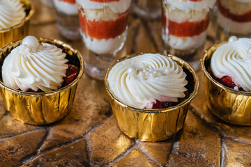 Cupcakes decorated with vanilla cream on New Year's Eve. On a copper tray in golden molds.