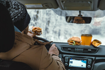 a man eats while driving a car. stop for lunch
