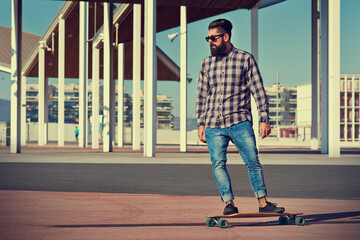 Obraz premium Skilled male skater riding longboard at city skate park