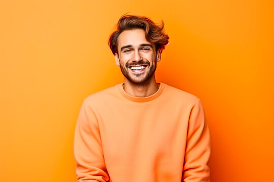 Homme sympathique avec une barbe posant avec un pull orange sur un fond orange