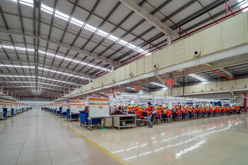 Female worker working in a garment factory in an industrial park in Ho Chi Minh City, Vietnam, with modern machinery and technology systems. - obrazy, fototapety, plakaty