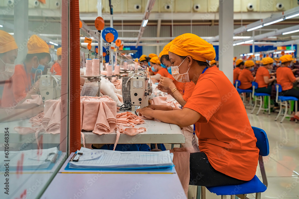 Wall mural Female worker working in a garment factory in an industrial park in Ho Chi Minh City, Vietnam, with modern machinery and technology systems.