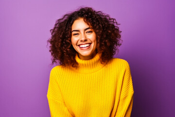 Fototapeta na wymiar Jeune femme souriante portant un pull jaune devant un fond violet