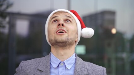 Smiling young businessman wearing Santa Claus hat while throwing money in the air outside. Business, celebration, New Year concept. Slow motion - Powered by Adobe