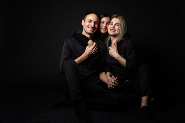 Happy young family with one child having fun together isolated on black.