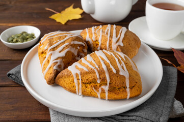 Traditional pumpkin scones with cinnamon, anise and sugar glaze on top. Autumn dessert.