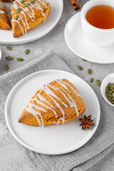 Traditional pumpkin scones with cinnamon, anise and sugar glaze on top. Autumn dessert.