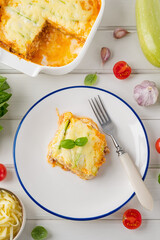 Delicious zucchini lasagna with sauce bolognese on a plate on a white wooden bachground. Healthy food. Top view. Selective focus.