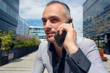 successful businessman outdoors talking on phone with his employees.