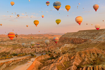 In Cappadocia, balloons ascend into the heavens. Radiant balloons seize the dwindling sunlight, projecting a mystical radiance upon the surreal peaks below them in Goreme region of Cappadocia, Turkey.
