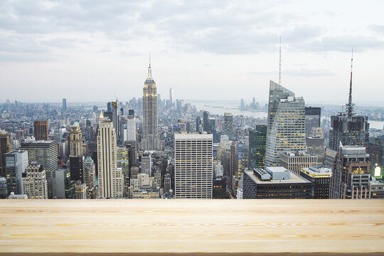 Empty wooden table top with beautiful New York skyscrapers at daytime on background, mock up