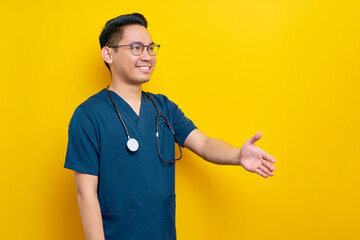 Handsome young Asian man doctor or nurse wearing a blue uniform and glasses standing confidently...