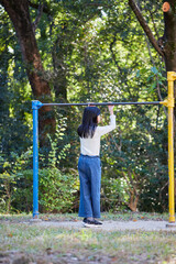 秋の公園で鉄棒を遊んでいる小学生の女の子の様子