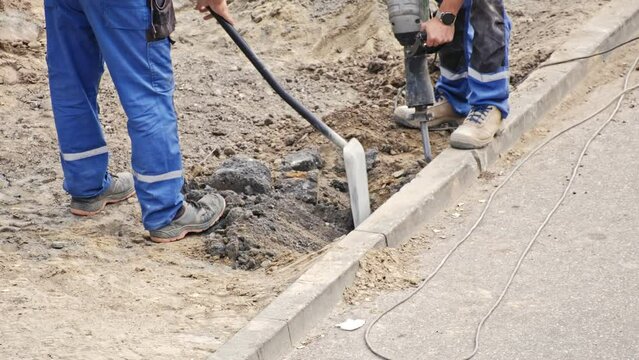 Roadworks Construction Site Conctractor Replacing Concrete Curb Brick using Shovel and Pneumatic Hammer