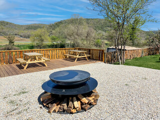 Camping site with fire pit and wooden desks and deck, mountain view in the background