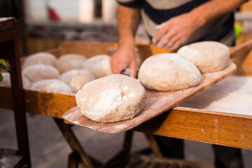 Wheat dough shaped into loaves arranged in rows on the table before baking