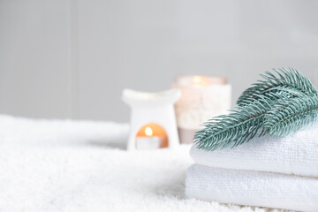 Obraz na płótnie Canvas Fresh white towels with fir branch, candles and Christmas decorations. Wellness and wellbeing. SPA massage or beauty salon, relaxation and self care in Christmas or New Year variant. Copy space.
