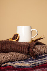 Cozy winter lifestyle concept. Cup of hot drink with warm knitted clothes.	