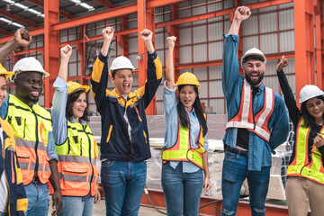 group of male employees, engineers, and female workers wearing uniform jackets Co-workers raised their hands in joy after the meeting ended before the start of production of machinery in the factory.