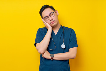 Young Asian man doctor or nurse wearing a blue uniform and glasses resting his head on his hands...