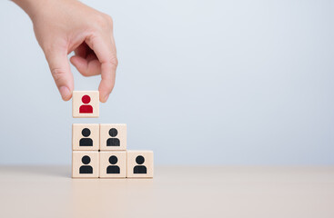 Human resources management and business hire recruitment concept. Corporate hierarchy, recruiter to complete team by leader person, professional staff search. Hand hold red people icon on wooden cube.
