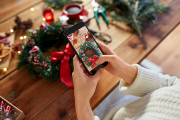 winter holidays, diy and hobby concept - close up of woman with smartphone photographing handmade...