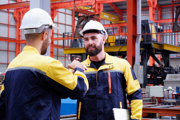 Engineers standing smiling and holding hands in a factory.