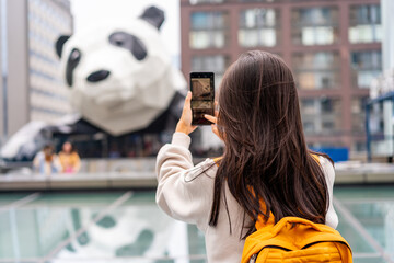 Young woman traveler takes a photo of a giant panda statue while traveling in Chengdu, China © Kittiphan