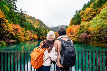 Young couple tourist looking at beautiful autumn scenery landscape at jiuzhaigou national park in Chengdu, China