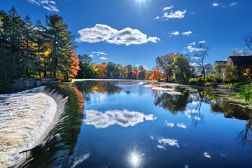 Weir on the Charles River and fall sunshine reflecting in the water at South Natick Dam Park - obrazy, fototapety, plakaty