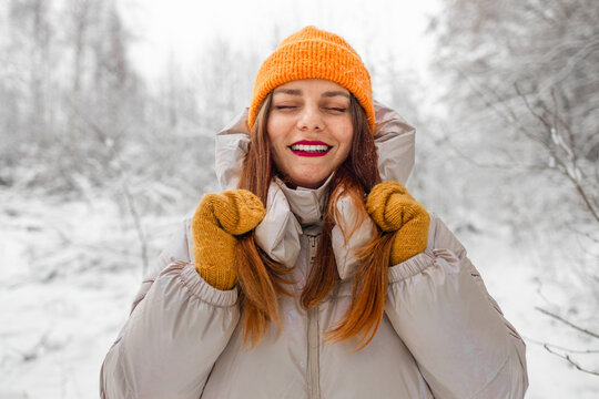 Portrait of happy beautiful girl, young joyful positive woman walking playing with snow, snowflakes, having fun outdoors in winter clothes, hat, smiling. Winter season, weather. High quality photo