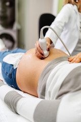 Female doctor doing ultrasound scan for a beautiful pregnant woman. Side view. Modern pregnancy  and healthcare concept.