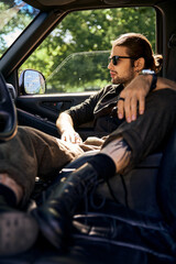 handsome eye catching male model in elegant black outfit with accessories relaxing in his car