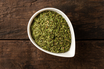 Dried lovage in bowl on retro wooden background. Top view