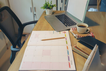 Agenda, planner book, laptop, 2024 calendar, pencil, and cup of coffee place on business office...