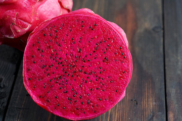 Slices of red dragon fruit on a wooden table. Red Dragon Fruit is also known as Pink Pitaya or Strawberry Pear.       