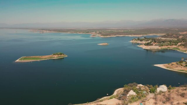 Aerial drone flying over a lake, water dam, with mountains at sunrise. Beautifull dreamy landscape view. Coastline with boats. Pacefull landscape. Cabra Corral, Salta Argentina.