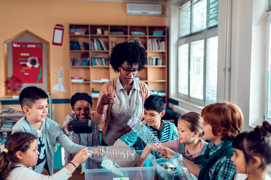 A teacher guides students in a recycling activity in the classroom