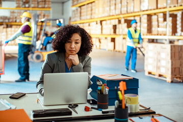 Focused Warehouse Manager Working on Her Laptop