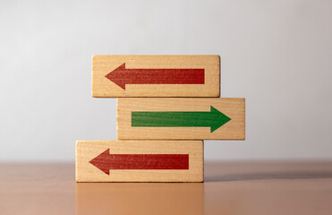 Conceptual image of choice and direction Wooden blocks with arrows pointing in opposite directions....