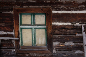The window in the log cabin has a sturdy wooden frame, providing a rustic and natural appeal to the space.