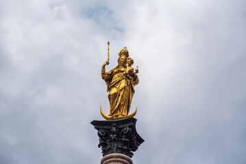 Fototapeta na wymiar Golden statue of Mary on top of Mariensaule located on the Marienplatz in Munich